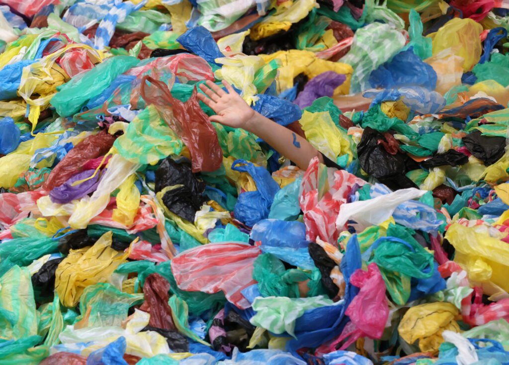 montagne de sacs plastiques colorés avec une main qui dépasse