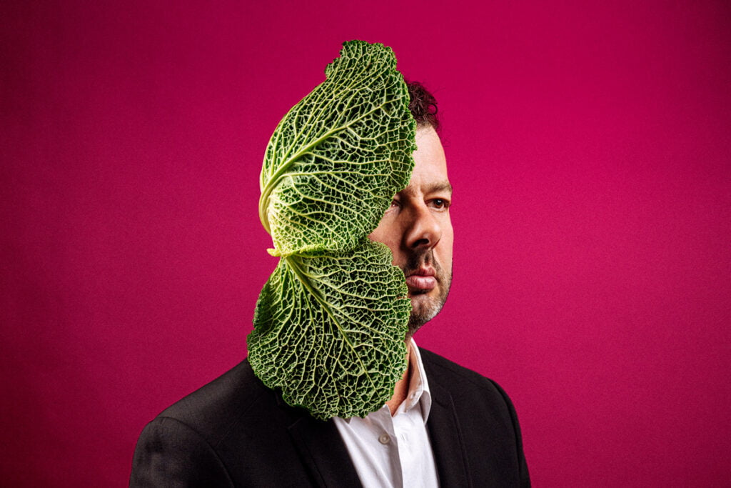 Portrait de Daniel Zimmermann avec deux feuilles de chou qui recouvrent une partie de son visage